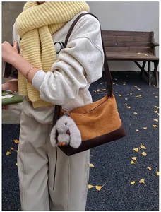 Detalle del bolso plisado caramelo con colgante de conejo de peluche en entorno otoñal