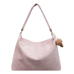 Pink suede large tote bag with shoulder strap and woven pendant on white background
