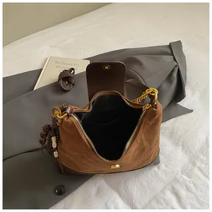 Retro brown quilted suede tote bag with golden chain and bead charm on gray blazer