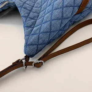 Close-up of adjustable brown leather strap and silver buckle on quilted denim tote bag