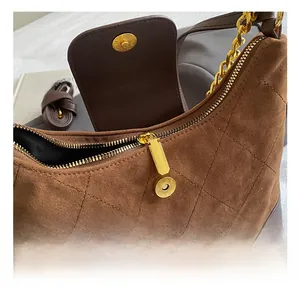 Close-up of brown suede tote featuring quilted stitching, gold chain, and hardware details
