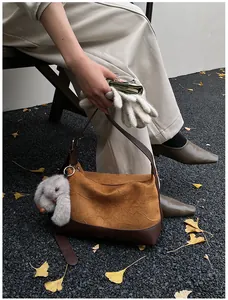 Bolso tote vintage color caramelo con colgante de conejo sobre hojas de ginkgo otoñales