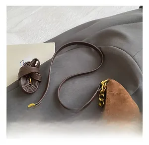 Detail of brown suede tote bag featuring gold chain and premium quilted leather straps