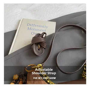 Detailed shot of brown suede tote featuring adjustable strap and wooden bead charm