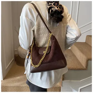 Close-up of quilted suede and leather shoulder bag with gold chain and tassel detail