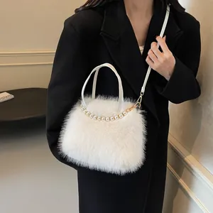 Detail der weißen Plüsch-Handtasche mit elegantem Perlenbesatz und goldenem Metallgurt