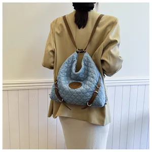 Quilted light blue denim tote with brown leather straps and M logo on a model back