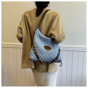Detail of blue denim tote bag with diamond quilting and metallic M logo emblem