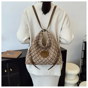Detail of brown quilted tote bag with M logo patch and leather straps on model