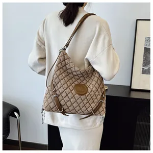 Detail of vintage brown quilted tote bag with letter M logo and chain accents