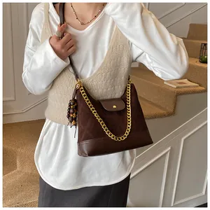 Detail of brown suede tote bag with gold chain strap and wooden bead charm accessory