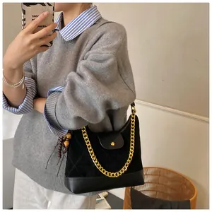 Detail of black quilted suede tote with gold chain strap and wooden bead pendant accessory