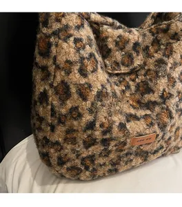 Close-up of leopard print plush shoulder bag showing soft faux fur texture and brand label