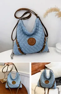 Detail of light blue quilted denim bag with leather trim and silver chain strap