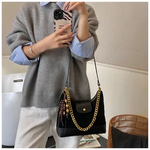 Close-up of black suede shoulder bag featuring a gold chain and wooden bead tassel