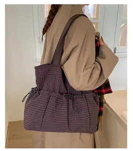 Detail of purple plaid tote bag with functional drawstring pocket and brown strap