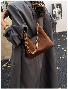 Detail of suede patchwork tote bag with gold chain strap and decorative tassels
