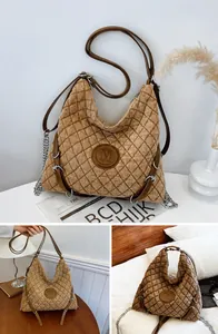 Close-up of khaki quilted tote bag featuring a leather M patch and metal chain detail