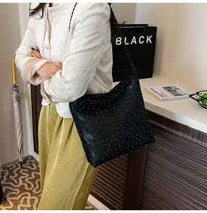 Detail of black hobo bag with sparkling finish and textured woven rope shoulder strap