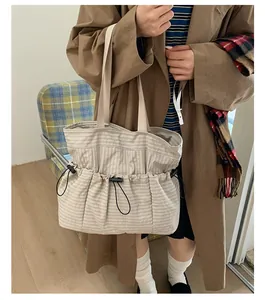 Detail of beige checkered canvas tote bag with drawstring design and black hardware