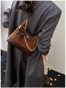 Detail of vintage brown suede crossbody bag with gold chain and wooden bead charm