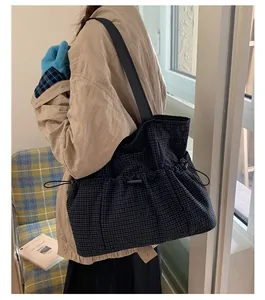 Detailed view of large plaid tote bag with side drawstring and woven shoulder strap