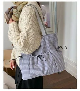 Detail view of large plaid tote bag with side drawstring pockets and durable grey straps