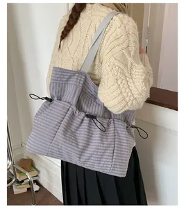 Detail of grey checkered tote bag with drawstring utility pockets shown on a model
