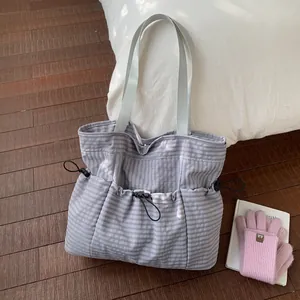 Detail of light purple checkered tote bag featuring multiple pockets and drawstring buckles