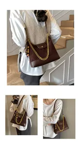 Detailed view of dark brown suede shoulder bag with gold chain and beaded tassel