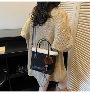 Detail of suede bucket bag with white faux fur trim, round handles and tassel charm