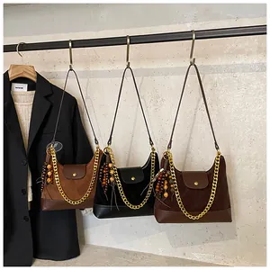 Detailed view of suede hobo bags in three colors with gold chains and beaded tassels