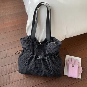 Detailed view of black checkered tote bag with drawstring closure on a cozy home background