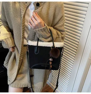 Detail of suede bucket bag with faux shearling trim, pompom charm and beaded handle