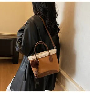 Detail of suede bucket bag with faux fur trim, decorative tassels and brown leather handles
