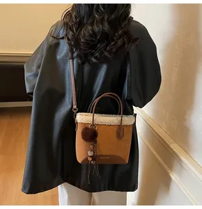 Close-up of brown suede bucket bag with white faux fur trim and plush ball charm