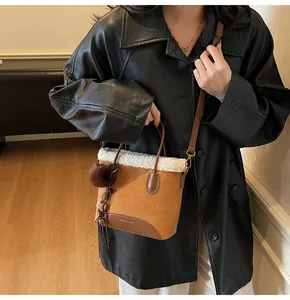 Brown suede bucket bag with white faux fur trim and fashion charm detail view