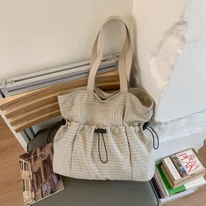 Large khaki checkered tote bag with drawstring closure on a chair in a cozy setting