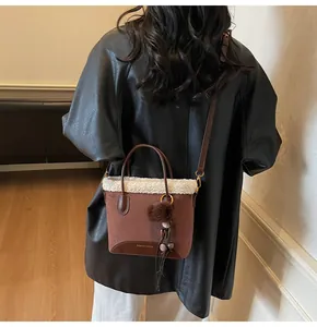 Brown suede bucket bag with white fur trim and pom-pom shown on model shoulder
