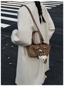 Bolso tote de ante marrón con amuleto de cachorro llevado por modelo en la calle