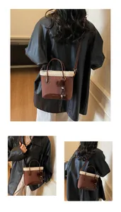 Detail of brown suede bucket bag with white faux fur trim and fluffy pom-pom charm