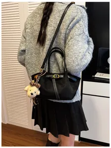Detalle de bolso hobo de ante negro con hebilla dorada y colgante de oso de peluche