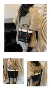 Detail view of black suede bucket bag with white faux fur trim and furry ball pendant
