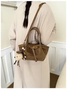 Detalle de bolso tote de ante marrón con correas y colgante de perrito decorativo suave