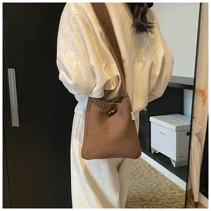 Detail of dark brown chunky knit crossbody bag with a horn button and woven texture