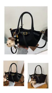 Detalle del bolso tote de ante negro con hebilla dorada y colgante de oso de peluche