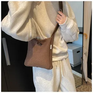 Brown knit crossbody bag featuring a toggle button closure and white woven brand label