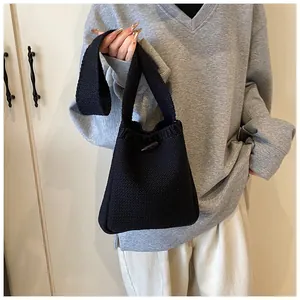 Close-up of black knitted texture on the handbag featuring a dark brown toggle button