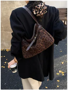 Outdoor shot of a leopard print faux suede tote bag with brown leather shoulder straps