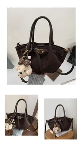 Detalle del bolso tote de ante marrón oscuro con colgante de perrito y hebillas doradas